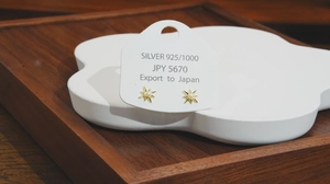 Close-up of S925 silver starburst pearl earrings on a cloud-shaped display stand