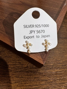 Close-up of S925 silver cross earrings with natural pearls on a wood background
