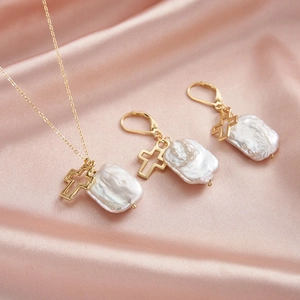 Détail du parure en perles baroques avec pendentifs croix évidés sur soie rose