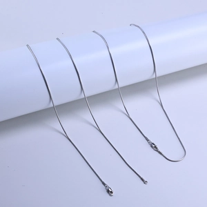 Close-up of three 925 silver snake chains with lobster clasps on a white display stand