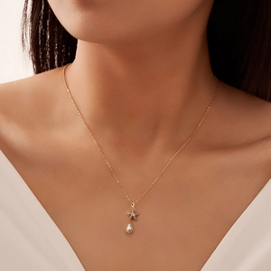 Gold starfish pendant necklace with white teardrop pearl on female model neck