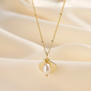Detailed close-up of shell pendant with teardrop pearl on gold-plated silver necklace