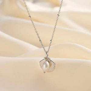 Detail of S925 silver shell pendant necklace with a natural freshwater pearl on beige silk