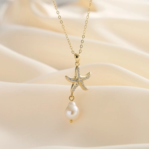 Detailed close-up of a gold starfish pendant necklace with pearl on soft silk fabric