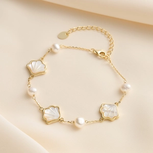 Detail of 925 silver gold bracelet with baroque pearls and white shell charms on silk