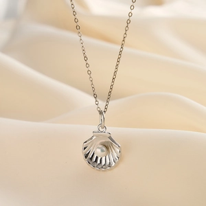 Gros plan du collier pendentif coquillage avec perle d'eau douce sur soie beige