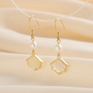 Macro shot of 14K gold pearl earrings with mother of pearl shell charms on silk