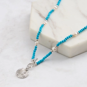Macro detail of shell pendant necklace with turquoise beads and pearl accents