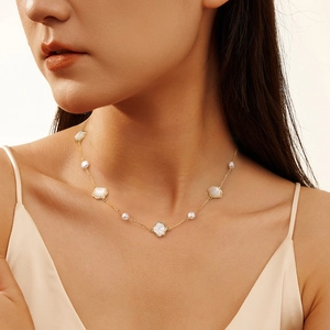 Elegant gold necklace with white mother of pearl flowers and pearls on silk dress
