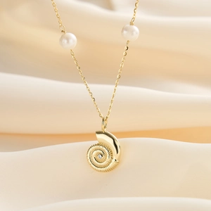 Close-up of golden shell pendant with sparkling zircon and white pearls on gold chain