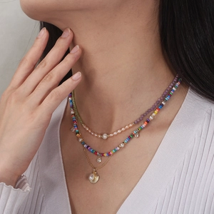 Three-layer bohemian beaded necklace set with shell pendant and pearls worn by a model