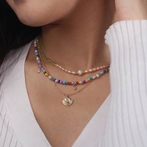 Détail d'un collier multicouche avec perles colorées et un pendentif coquillage doré