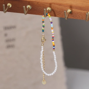 Detail of colorful seed bead and pearl bracelet hanging on a rustic wooden stand