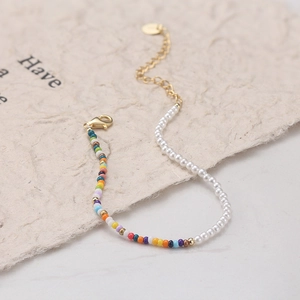 Detail of colorful beads and white pearls bracelet with gold lobster clasp and extension chain