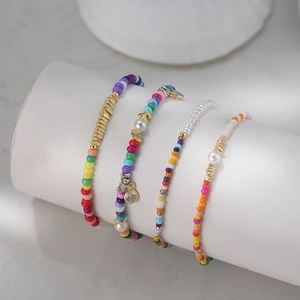 Set of four colorful beaded bracelets with gold charms and pearls on a white display
