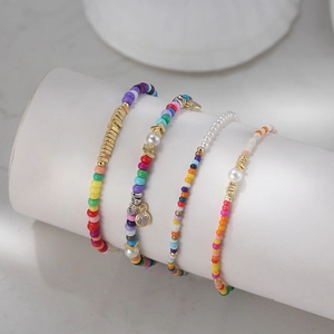 Macro detail of colorful beaded bracelets with gold charms on a marble display