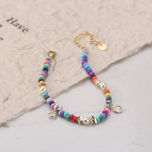 Détail d'un bracelet en perles colorées avec perles blanches, zircon et chaîne dorée