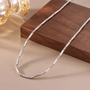 Close-up of S925 sterling silver bamboo style chain on a wooden display stand