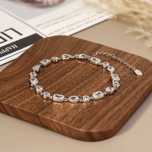 Macro detail of S925 silver bracelet featuring claw-set zircon stones on walnut wood board