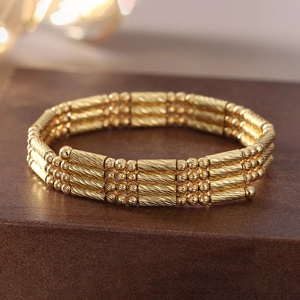 Close-up of gold-tone multi-layer spiral textured bracelet on a luxury surface