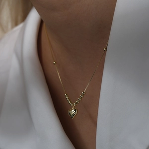 Polished golden 3D heart pendant necklace with decorative gold beads on a delicate chain
