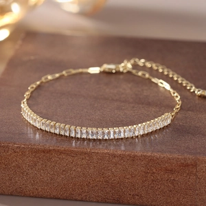 Macro shot of 18K gold plated bracelet featuring rectangular zircon stones on a wood base
