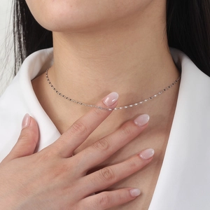 Close-up of a delicate S925 sterling silver figure-8 link chain on a woman neck