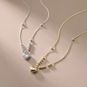 Detail of silver and gold heart pendant necklaces with a polished mirror finish