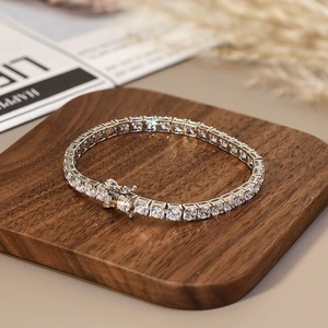 Détail d'un bracelet tennis en argent avec zircons ronds sur un présentoir en bois