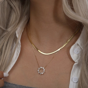 Close-up of a layered gold snake chain necklace set with a circular zircon pendant