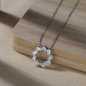 Detail of a silver circular pendant featuring micro-set baguette cut cubic zirconia stones