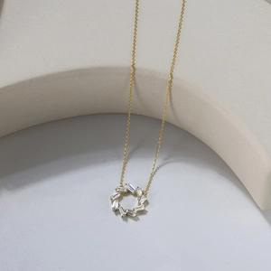 Close-up of baguette-cut zircon circle pendant on a fine golden chain necklace