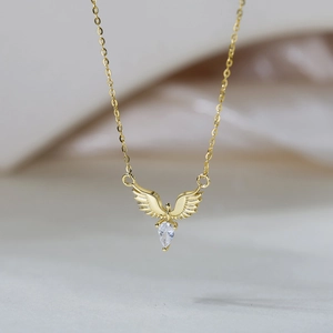 Détail macro du pendentif aile d'ange doré avec zircon poire sur chaîne fine