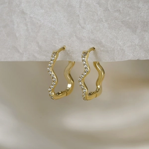 Macro shot of gold wave earrings featuring sparkling cubic zirconia on S925 silver base