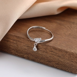 Close-up of s925 silver ring with zircon cluster and water drop pendant on wood