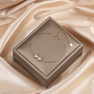 Detail of gold bow bracelet with heart-shaped cubic zirconia on silk fabric