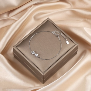 Detail of 925 silver bow bracelet with heart-shaped zircons on silk background