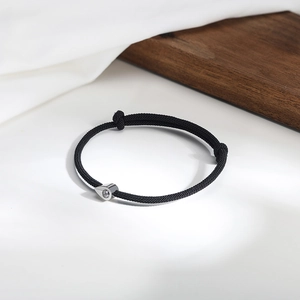 Detail of adjustable black braided cord bracelet with silver teardrop cubic zirconia charm