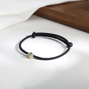 Close-up of adjustable black woven rope bracelet with 14K gold plated cubic zirconia charm