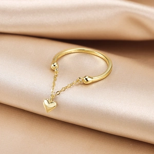 Close-up of S925 sterling silver stamp and heart tassel charm on gold adjustable ring