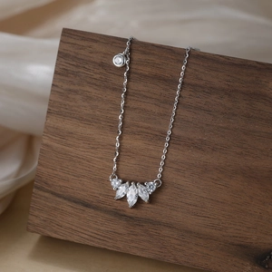 Macro detail of S925 silver necklace with marquise-cut zircon stones on a wooden stand