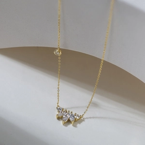 Detail of s925 silver gold necklace with marquise zircon pendant on white curved stand