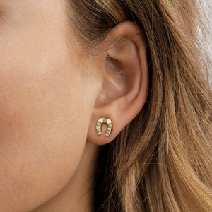Gros plan de boucles d'oreilles fer à cheval dorées avec zircons portées à l'oreille