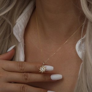 Gros plan d'un collier pendentif tournesol doré avec une pierre centrale sur un mannequin
