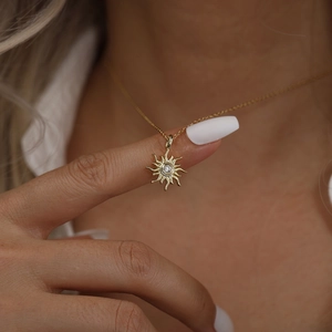 Collier avec pendentif soleil doré et pierre de zircon présenté sur un modèle