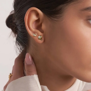 Detailed view of asymmetric 925 silver mushroom and butterfly stud earrings on ear