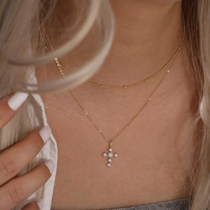 Détail d'un collier doré multicouche en argent S925 avec un pendentif croix en zircone