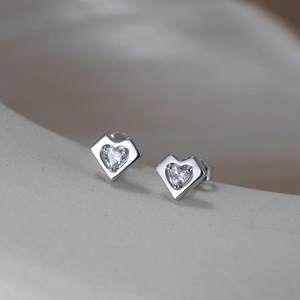 Detailed macro view of heart-shaped zircon earrings in silver minimalist setting