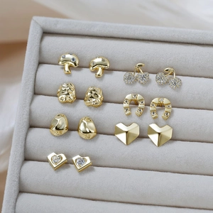 Detailed view of assorted gold heart and mushroom stud earrings in a velvet jewelry tray