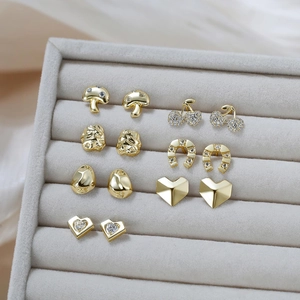 Détail de sept paires de boucles d'oreilles dorées géométriques avec zircons sur plateau